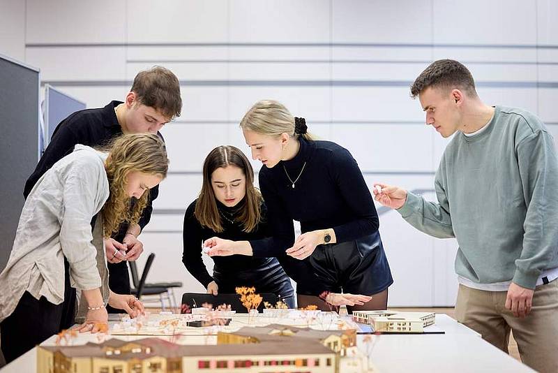 © HCW / Schedl Eine Gruppe steht um ein Architekturmodell und diskutiert dieses