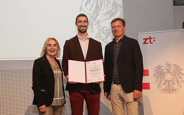 © BKZT/Gerhard Fally Junger Mann (Simon Kaufmann) hält strahlend seine Urkunde in die Kamera.