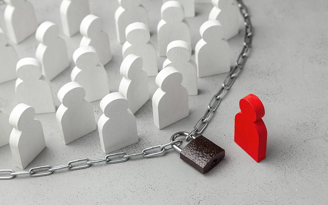 © iStock/ADragan mehrere weiße Figuren stehen innerhalb einer abgeschlossenen Kette, außerhalb eine rote Figur