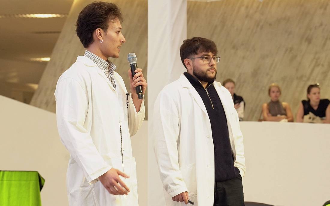 © WU Wien/Entrepreneurship Avenue Zwei Personen in Laborkitteln sprechen auf einer Präsentation