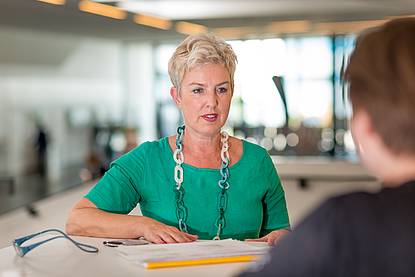 © HCW Dame mit kurzen blonden Haaren und Halskette in grünem Shirt