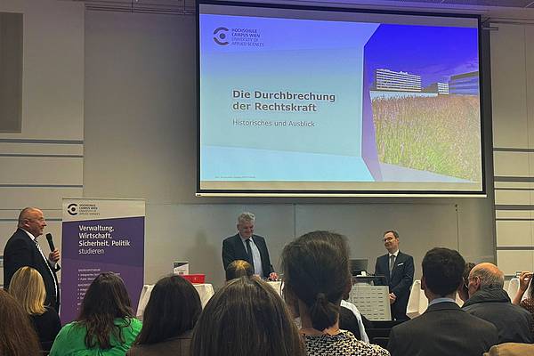 © HCW Der Vortragende steht am Rednerpult, hinter ihm die Folien, vor ihm das Publikum