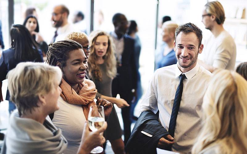 © G-Stock Studio//Shutterstock.com Eine Gruppe von Menschen auf einem Empfang im Gespräch