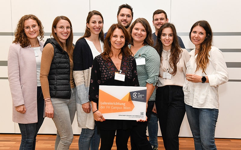 © HCW/Odorizzi Gruppenfoto mit neun Personen und eine Dame in der Mitte hält eine Lehreinrichtungstafel